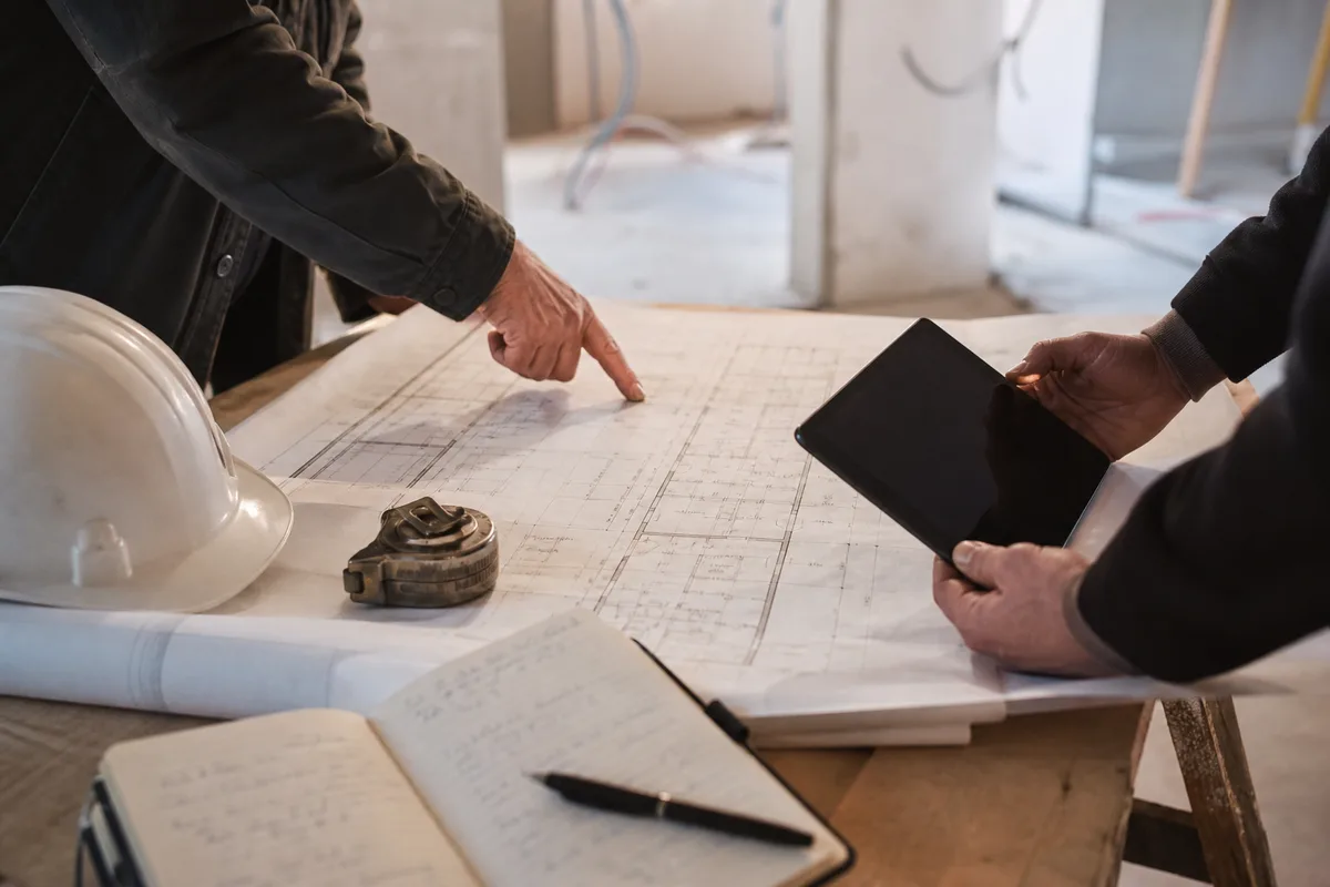 Réunion de chantier autour d’un plan déroulé dans un bâtiment en fin de travaux